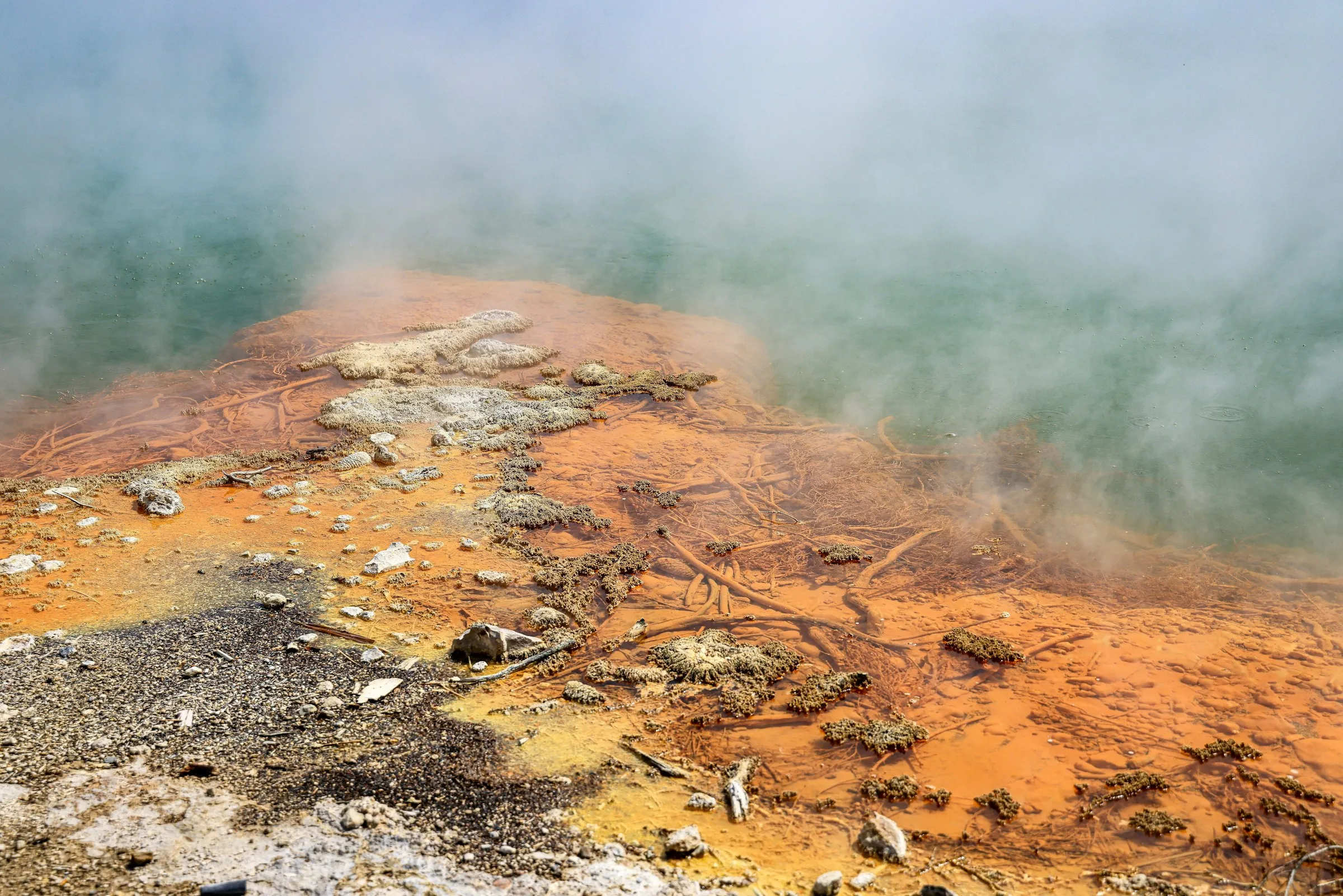Steam rising off the mineral-stained edge of a natural hot spring